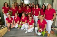 Frauen in einheitlichen roten T-Shirts stehen und knien in einer Gruppe zusammen
