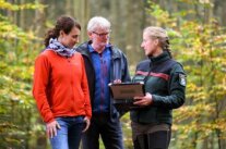 Zwei Personen mit einem Förster im Wald