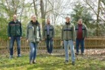 Foto zweier Frauen und dreier Männer in einem Garten