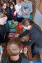 Kinder stehen am Tisch und nehmen Brot mit Butter von der Bäuerin entgegen