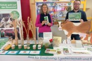 Mann und Frau stehen am Ausstellungsstand, vor ihnen Getreidesorten in Vasen und Gläsern