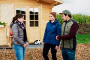 3 Personen stehen vor Fekleiner Hütte mit Katze und besprechen sich. ©Daniel Delang