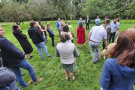 Seminar-Teilnehmer stehen auf Wiese und lauscht Vortrag 